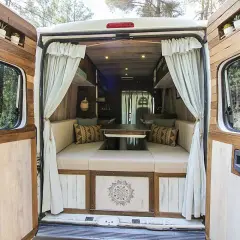 Interior de una caravana camperizada con asientos, mesa y decoración rústica. ¡Perfecta para aventuras!