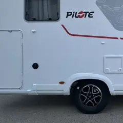 Autocaravanas con garaje, listas para la aventura. Detalle lateral de una autocaravana blanca con puerta de acceso y detalles gráficos.