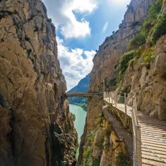 El sendero del koningspad en España, un camino de madera suspendido sobre un desfiladero con un río turquesa abajo.