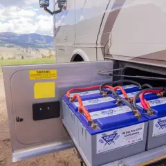 Baterías de litio de 100 amperios hora, 12 voltios, listas para alimentar una casa rodante en un paisaje montañoso.