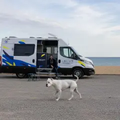 Un hombre y su perro blanco disfrutan de un día en la playa cerca de un pueblo teba.