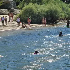 Gente disfrutando en la playa y el agua. Para llegar a esta playa, pita el camino.