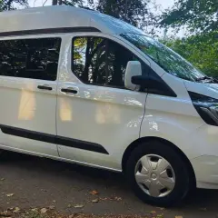 Furgoneta blanca Ford Transit tamaño mediano, lista para la aventura.