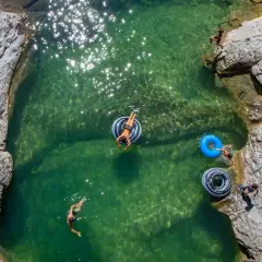 Disfrutando de las pozas cerca de Ainsa. Niños nadan y flotan en aguas cristalinas rodeadas de rocas.