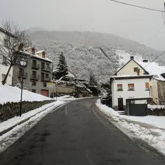 Un pueblo nevado, ideal para un fin de semana en Jaca. Casas de piedra y tejados blancos bajo un cielo gris.