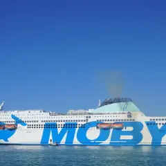 El ferry Moby Legacy, con su icónico diseño de ballena azul, navega rumbo a Cerdeña o Sicilia bajo un cielo despejado.