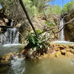 Cascada natural en las aguas termales Santa Fe, con rocas anaranjadas y vegetación exuberante.