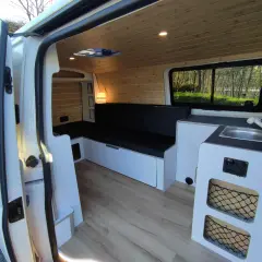 Interior de una Volkswagen T5 camperizada con asientos, cama, fregadero y armarios. Lista para viajar.
