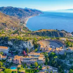 Vista aérea del antiguo teatro griego de Taormina, uno de los lugares más bonitos de Sicilia, con el mar azul y la costa al fondo.