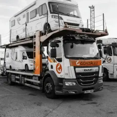 Camión transportando caravanas, dos vehículos recreativos apilados listos para su transporte.