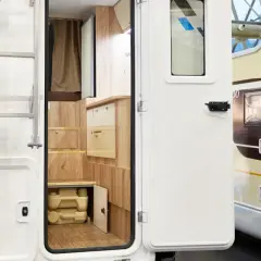 Detalle interior de autocaravana, mostrando un baño portátil y armarios de madera. Ideal para quienes buscan concesionarios de autocaravanas en Alemania.