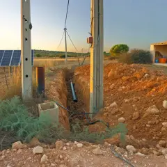 Instalación de paneles solares y zanja para cableado, mostrando cómo tener luz en el campo. Atardecer dorado.
