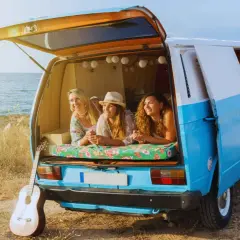 Tres amigas disfrutan de la vida en su furgoneta camperizada junto al mar. Inspiración para saber como camperizar una furgoneta.
