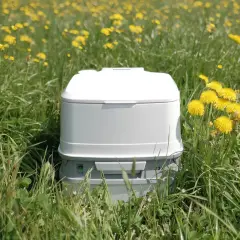 Un inodoro portátil blanco en un campo de flores amarillas. Así es como funciona un poti, una solución práctica para la naturaleza.