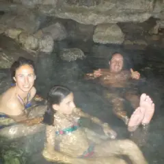 Familia disfrutando de las pozas termales del río Deva, rodeados de rocas y agua cálida.