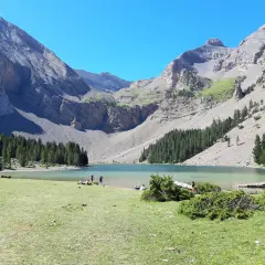Ibón de Plan con montañas, bosque y gente en la orilla.