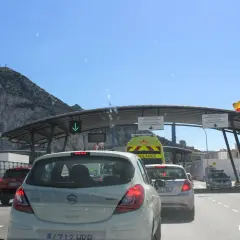 Fila de coches en la frontera de Gibraltar, con el Peñón al fondo. Señales indican dónde dove parcheggiare a Gibilterra.