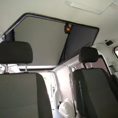 Interior de furgoneta con asientos delanteros y un techo elevable abierto, listo para la aventura.