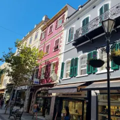 Edificios coloridos y tiendas en la Gibraltar altstadt, con gente paseando bajo un cielo azul brillante.