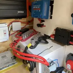 Sistema eléctrico con varios componentes, incluyendo un inversor, regulador solar y disyuntores. El grosor del cable eléctrico es notable en las conexiones principales.