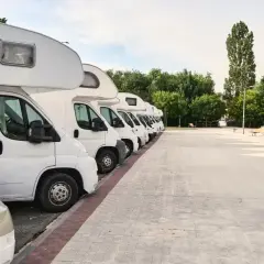 Fila de autocaravanas blancas aparcadas en un área de descanso. Consulta el precio parking caravanas para tu próxima aventura.