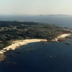 Vista aérea de la playa de Barreiro o Grove, con arena dorada, rocas y el mar azul.
