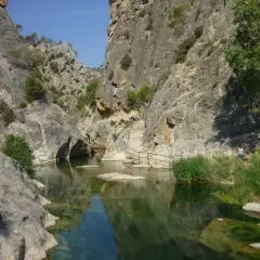 Un cañón con un río de aguas cristalinas y vegetación exuberante, ideal para disfrutar de los warmwaterbronnen in Spanje.