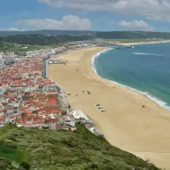 Vista aérea de Nazaré, Portugal, con su extensa playa dorada y el mar azul. Planifica tu viaje a Nazaré, Portugal, como llegar es fácil.