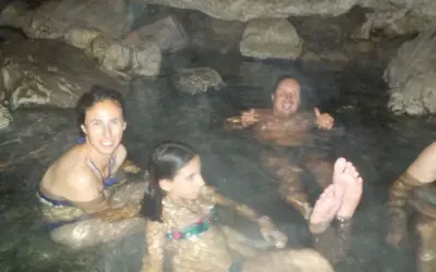 Familia disfrutando de las pozas termales del río Deva, rodeados de rocas y agua cálida.