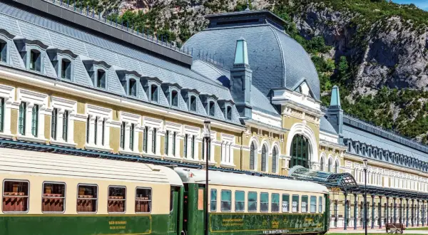 Estación de Canfranc, un lugar ideal donde comer bien en Jaca. Trenes clásicos esperan ante el imponente edificio.