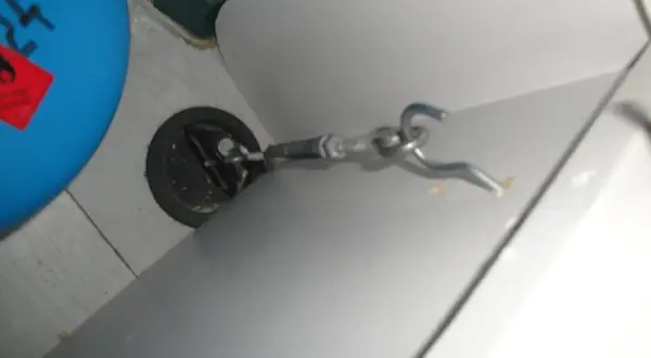 Detalle de cómo anclar muebles camper: un gancho metálico sujeto a un punto de anclaje en la pared de una autocaravana.