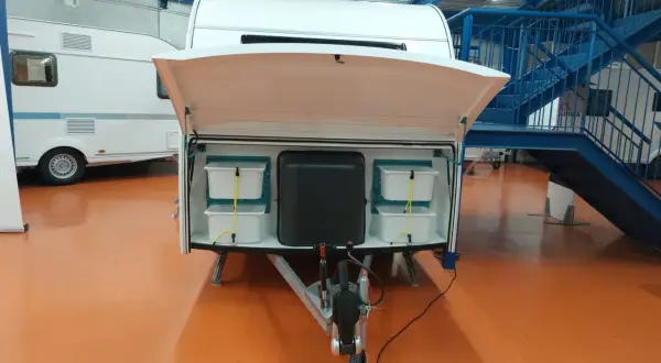 Detalle de la distribución de una furgoneta camper, mostrando compartimentos de almacenamiento y la lanza.