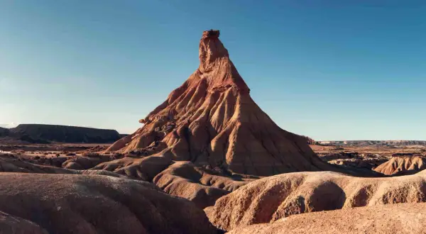 Paisaje desértico en Navarra, ideal para una aventura en camper. Formaciones rocosas erosionadas bajo un cielo azul.