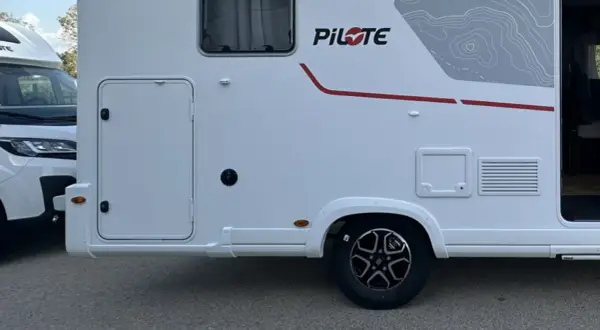 Autocaravanas con garaje, listas para la aventura. Detalle lateral de una autocaravana blanca con puerta de acceso y detalles gráficos.