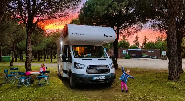 Autocaravana Benimar en un camping al atardecer. Niños jugando y disfrutando.