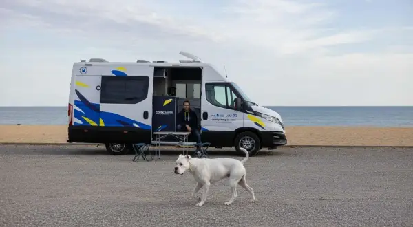 Un hombre y su perro blanco disfrutan de un día en la playa cerca de un pueblo teba.