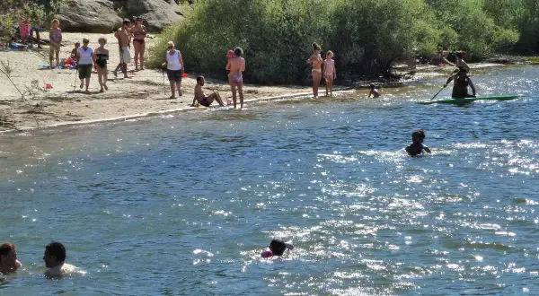 Gente disfrutando en la playa y el agua. Para llegar a esta playa, pita el camino.