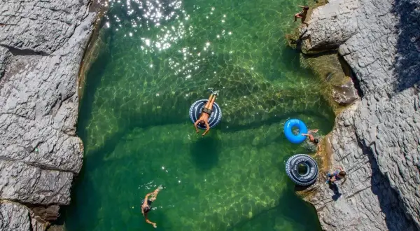 Disfrutando de las pozas cerca de Ainsa. Niños nadan y flotan en aguas cristalinas rodeadas de rocas.