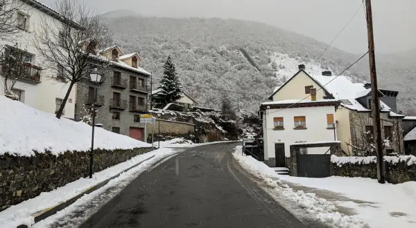 Un pueblo nevado, ideal para un fin de semana en Jaca. Casas de piedra y tejados blancos bajo un cielo gris.