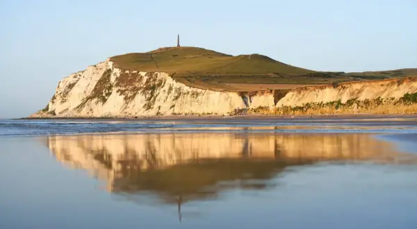 Acantilados blancos y verdes en Cap Blanc Nez, reflejados en el mar tranquilo.