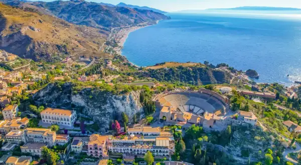 Vista aérea del antiguo teatro griego de Taormina, uno de los lugares más bonitos de Sicilia, con el mar azul y la costa al fondo.