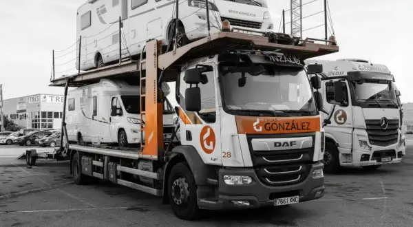 Camión transportando caravanas, dos vehículos recreativos apilados listos para su transporte.
