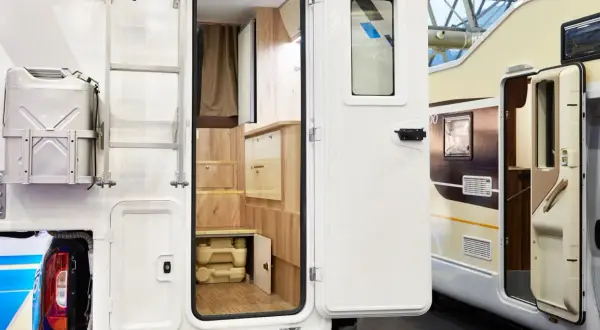 Detalle interior de autocaravana, mostrando un baño portátil y armarios de madera. Ideal para quienes buscan concesionarios de autocaravanas en Alemania.