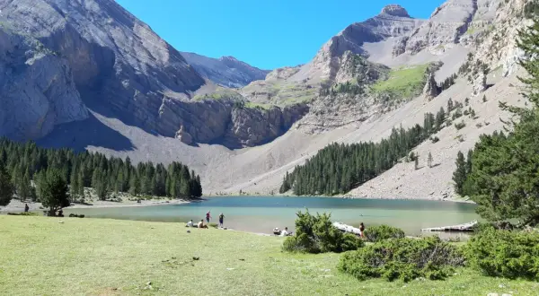Ibón de Plan con montañas, bosque y gente en la orilla.