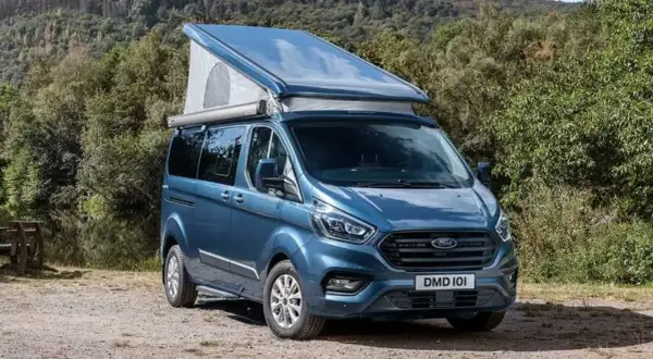 Furgoneta camper azul Westfalia Nugget con techo elevable, lista para una aventura en la naturaleza.