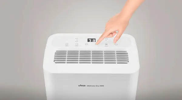 Mano ajustando la velocidad de un deshumidificador Ufesa Wellness Dry 2000. ¡No gasta mucho!