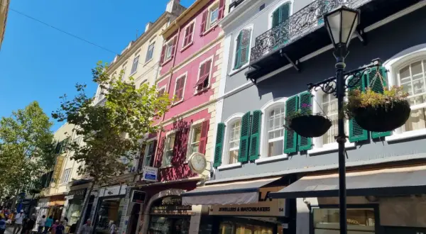 Edificios coloridos y tiendas en la Gibraltar altstadt, con gente paseando bajo un cielo azul brillante.
