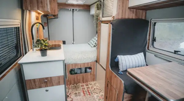 Interior de camper con cama, cocina y zona de asientos. ¡Ideas camper para tu próxima aventura!