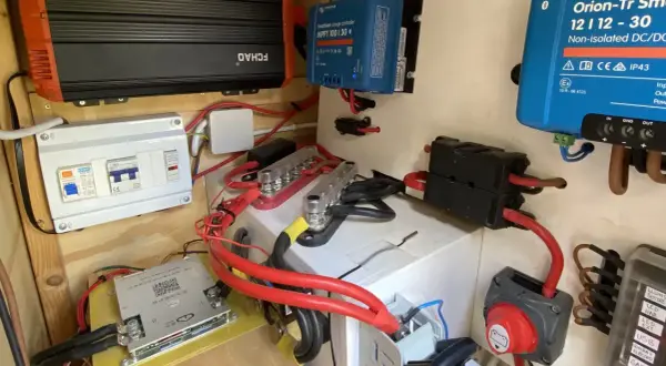 Sistema eléctrico con varios componentes, incluyendo un inversor, regulador solar y disyuntores. El grosor del cable eléctrico es notable en las conexiones principales.