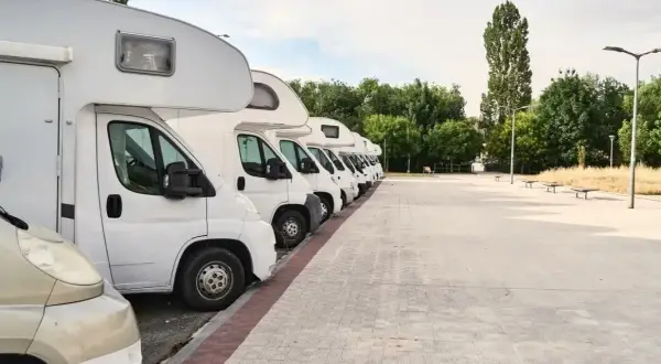 Fila de autocaravanas blancas aparcadas en un área de descanso. Consulta el precio parking caravanas para tu próxima aventura.